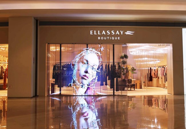 Transparent LED walls display images of virtual digital people on the glass of clothing stores